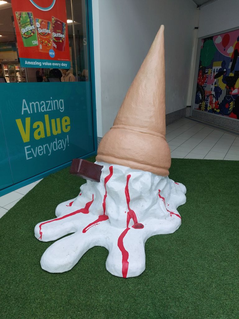 a sculpture of an oversized upside down melted ice cream outside a poundland shop